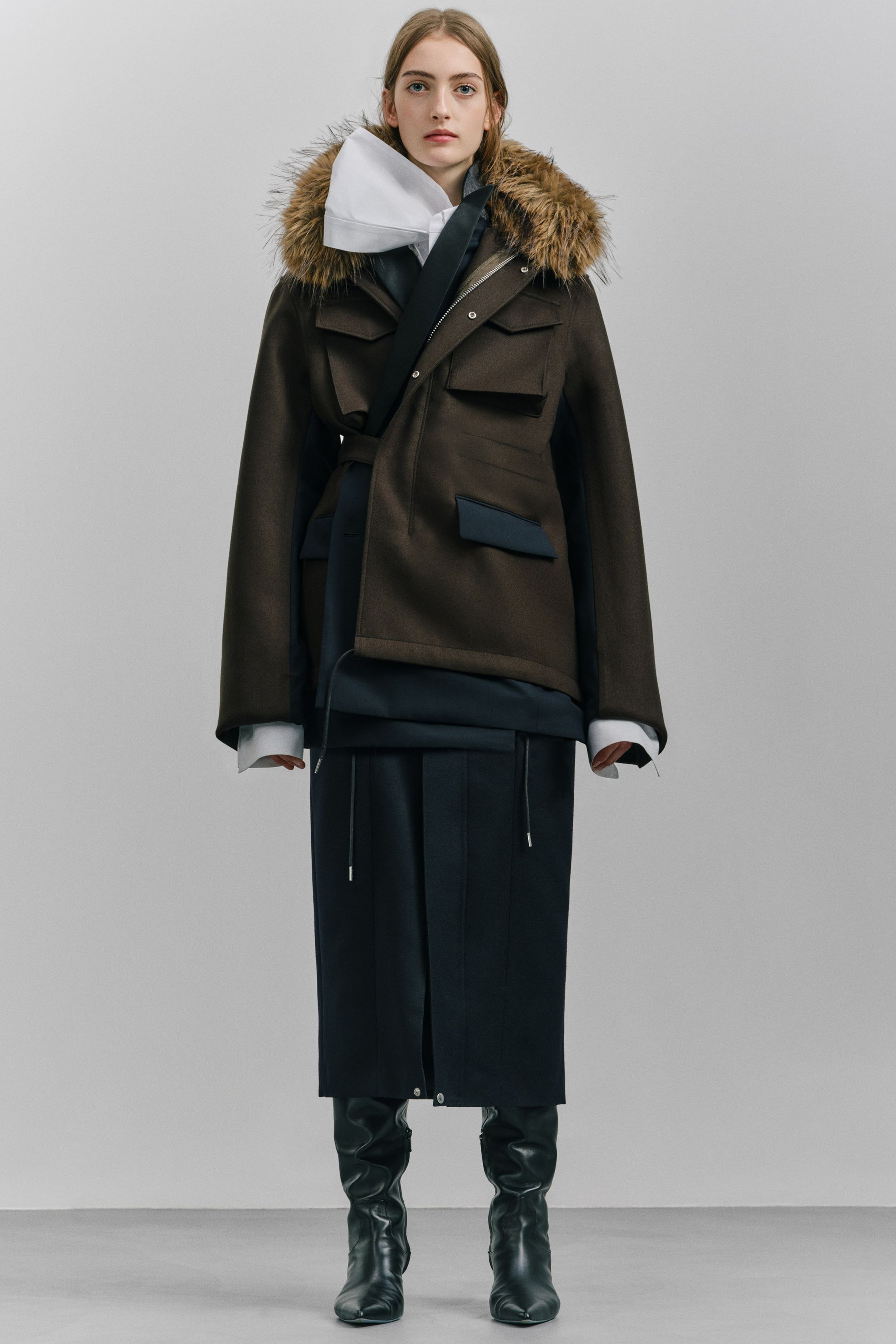 Sacai 本季继续以混合结构著称：羽绒服与西装外套、羊羔毛夹克与功能口袋结构交织在一起，打造层次丰富的机能时装。深色调与厚重面料让整体视觉更稳重，同时保持品牌标志性的结构拼接-顽石频道趋势研究
